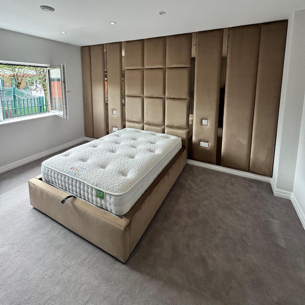 Modern bedroom with a grey double bed frame and padded wall paneling