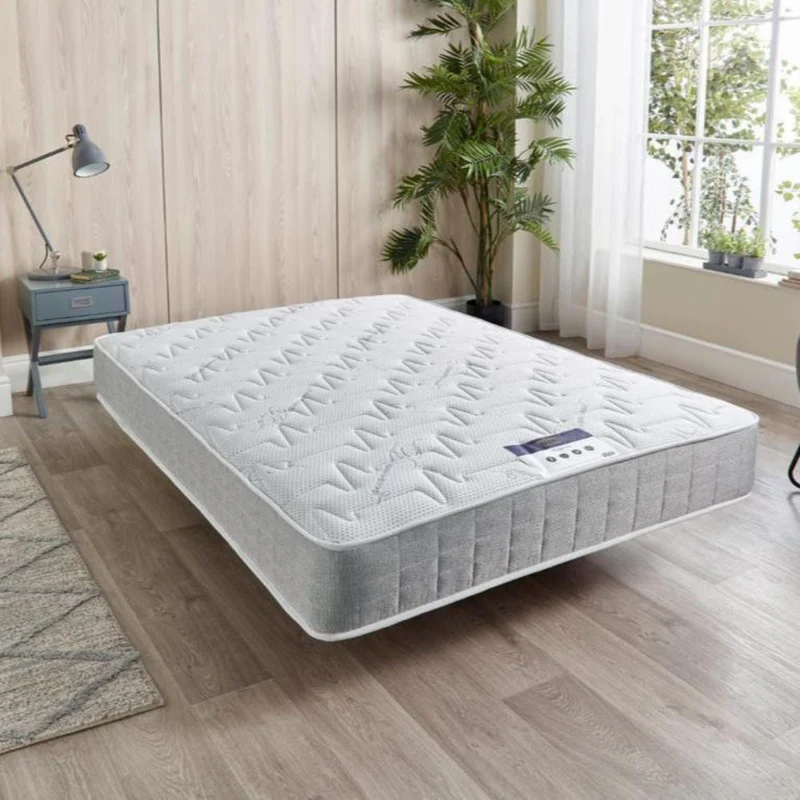 King-size mattress in a bright room with wooden flooring and plants.