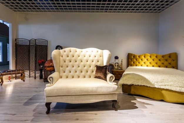 A luxurious room with a beige tufted luxury sofa bed and a golden tufted bed.