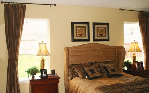 Bedroom with a rattan headboard, bed, and two framed artworks above.