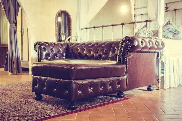 Vintage-style dark brown tufted leather single sofa bed in a cozy room setting.