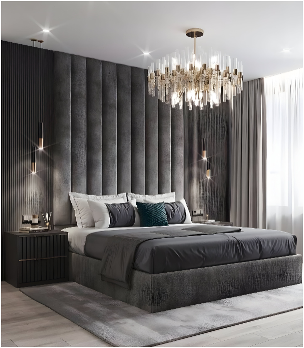 The image is of a bed with a chandelier hanging above it. The room also features upholstered wall panels. It is an indoor setting with interior design elements such as a pillow, curtain, and window treatment.