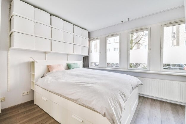 White single bed with storage drawers in a bright, minimalist bedroom.