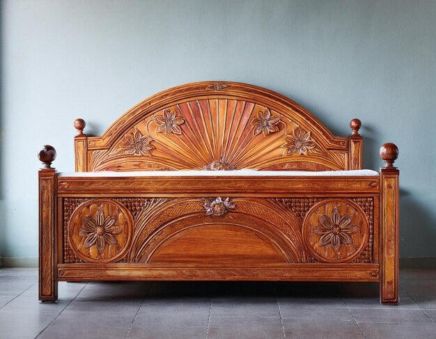 Intricately carved wooden sleigh bed with floral and sunburst designs.