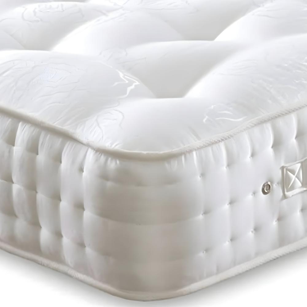 A close-up of the Kingsbury Hotel Luxury Organic Memory Foam Mattress shows its plush, white quilted surface. The top layer features subtle patterns, while the sides have a textured quilted design with small, indented squares. A fabric handle, secured by stitching and metal rivets, adds convenience, highlighting the mattress's soft, cushioned layers.