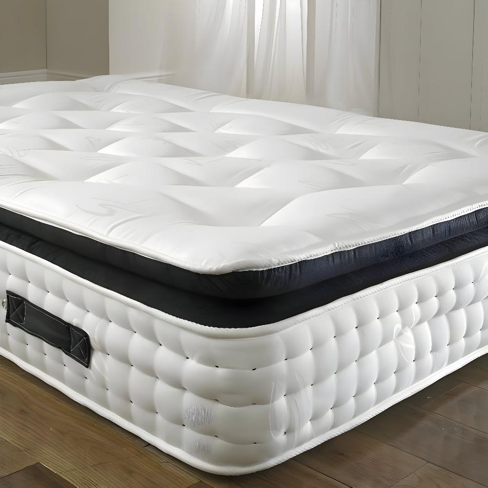 The image shows a luxurious pocket spring pillow top organic mattress with an impressive and plush design, set up in a minimalistic room. The mattress has a thick, quilted white topper with a pattern of squares that create a soft and cushioned appearance. This topper is complemented by a dark, contrasting layer underneath, suggesting additional support. The base of the mattress is tufted with evenly spaced, rounded indents, contributing to its elegant and high-end look. 