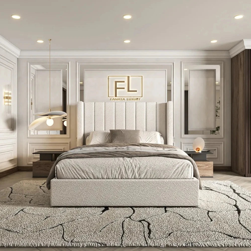 The image showcases The Manhattan Lined Wing Back Bed Frame in a stylish bedroom. The large bed features a tall, tufted light beige headboard with decorative pillows. A textured black and gray rug surrounds the bed, flanked by matching nightstands—one with an elegant pendant lamp and the other with a warm spherical lamp. The white paneled walls are complemented by large mirrors beside the headboard, and the "FL" logo with "FAMAYA LUXURY" is displayed above.