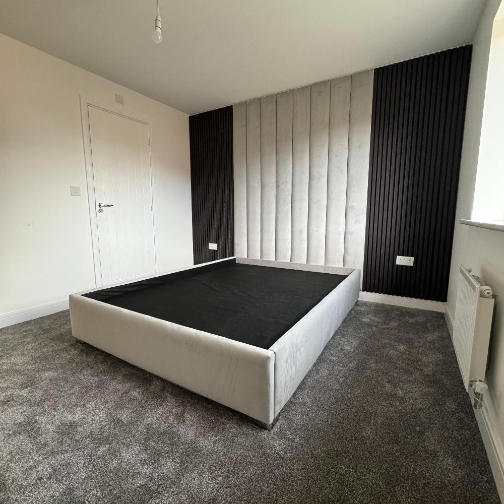 Minimalistic bedroom with gray aku panel bed frame and vertically paneled back wall.

