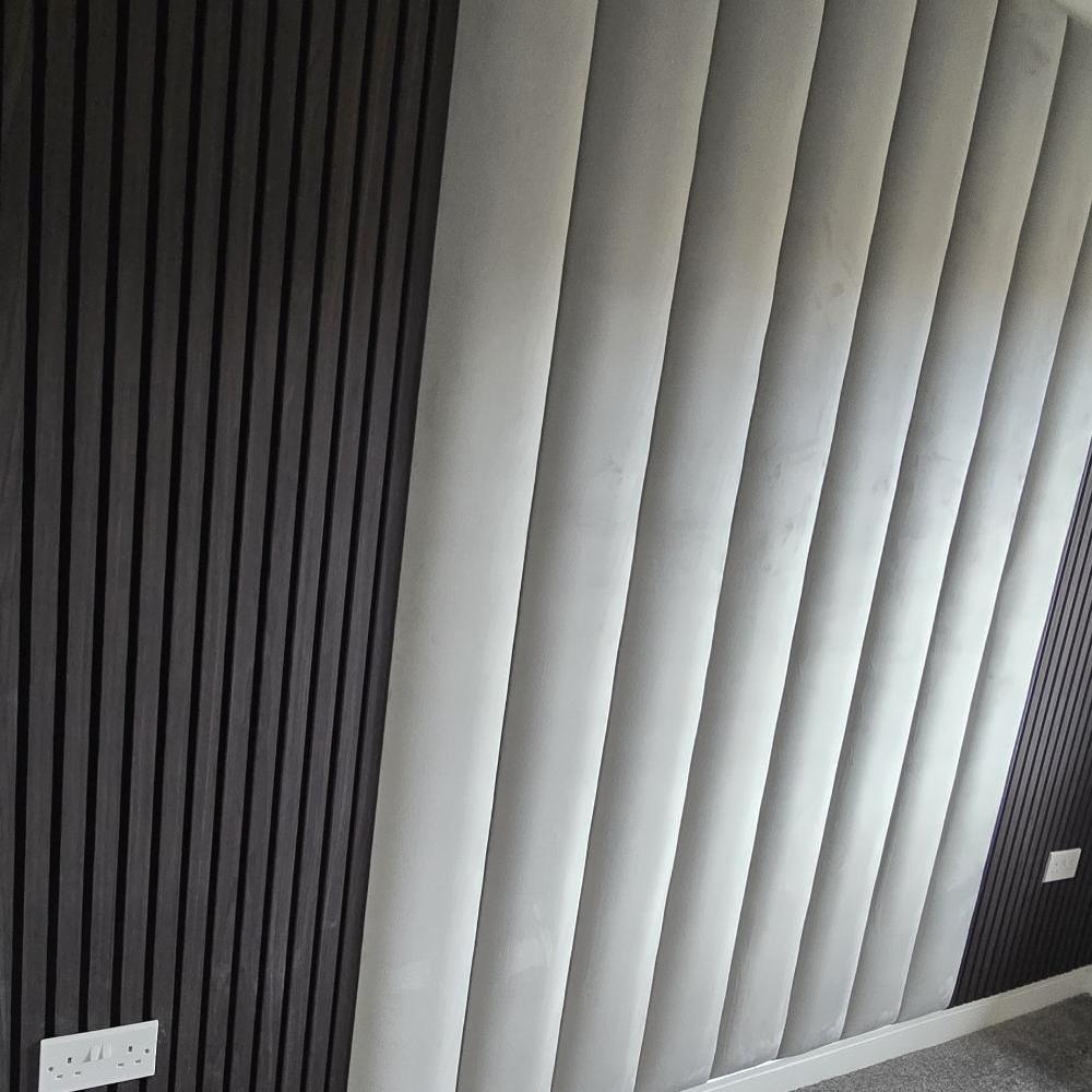 Wall with black ridged aku panels and light grey padded sections, featuring a white electrical outlet.

