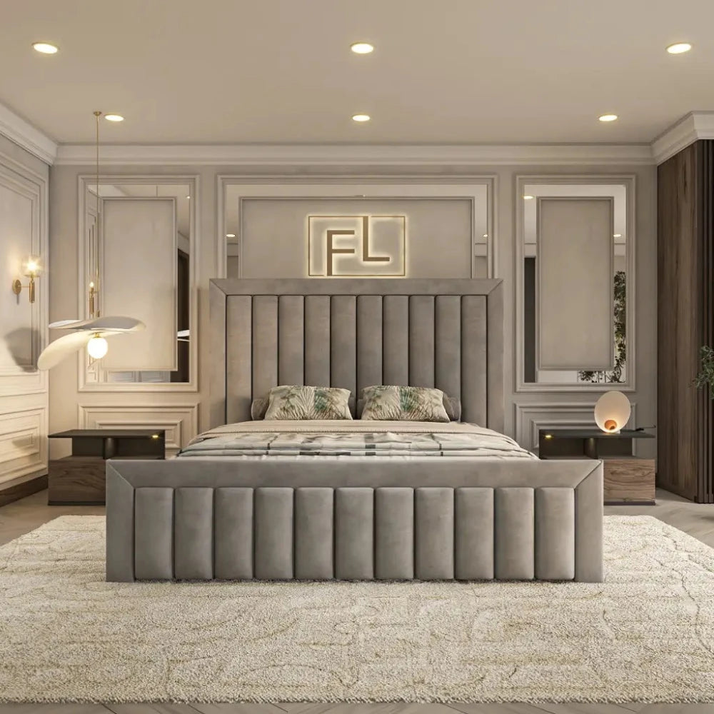 The Regency Bed Frame commands attention in this sleek modern bedroom, featuring a tall, padded headboard with vertical tufting and light-colored bedding. Flanking nightstands with decorative lamps enhance the elegance, while large mirrors and illuminated "FL" letters add contemporary flair. Recessed lighting and a plush rug complete the sophisticated atmosphere.